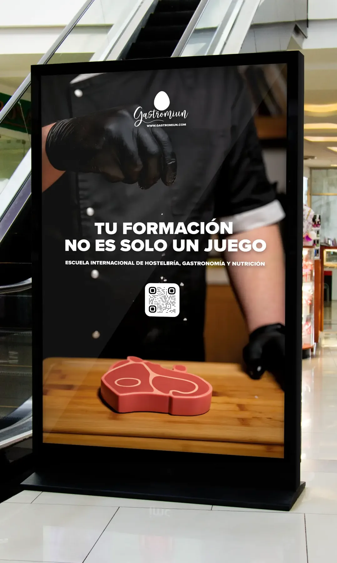 Montaje de soporte digital de Gastromiun con cocinero y chuletón de juguete bajo el titular de la campaña