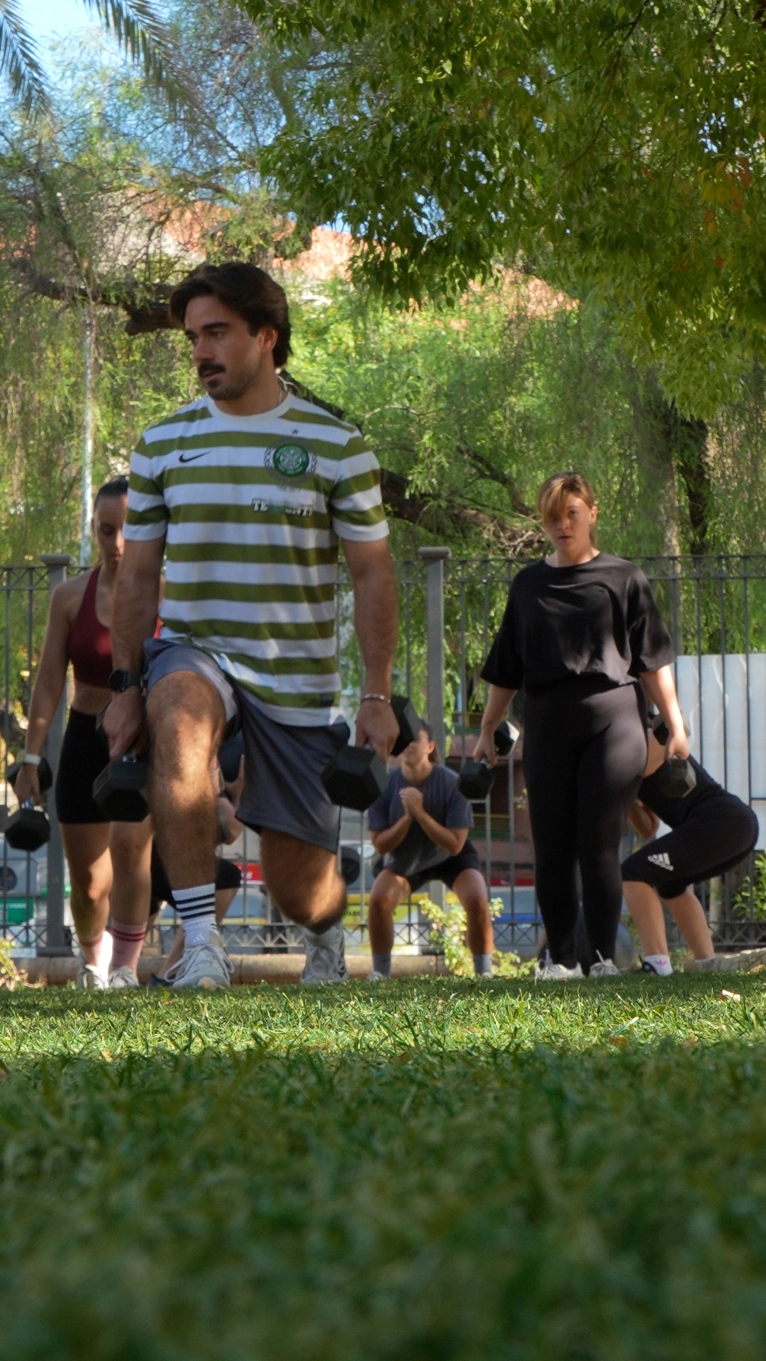 Un participante realiza un ejercicio de pie en la zona de entrenamiento a la sombra.