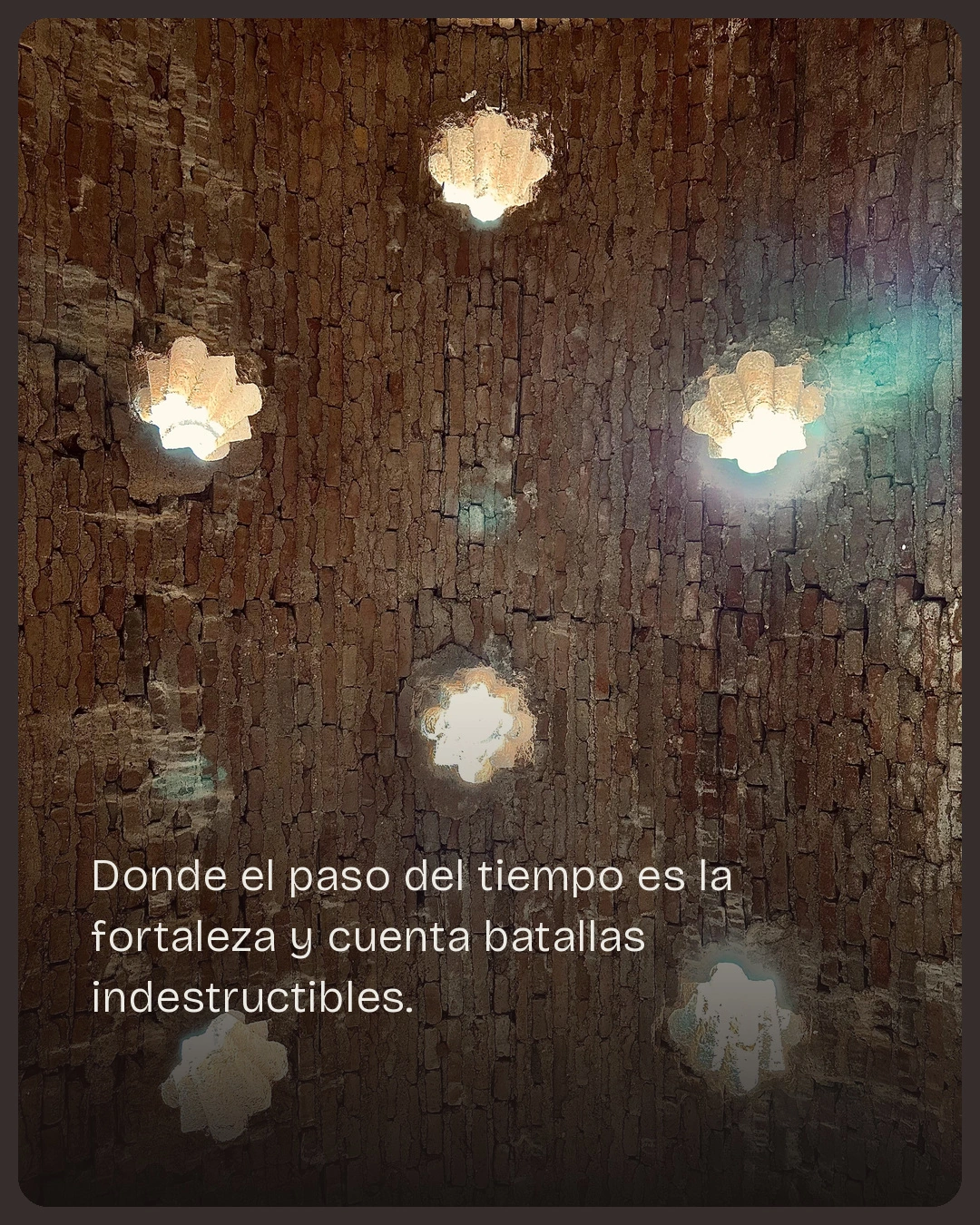 Munya Studio · Lámparas decorativas iluminan una pared de piedra con textura.