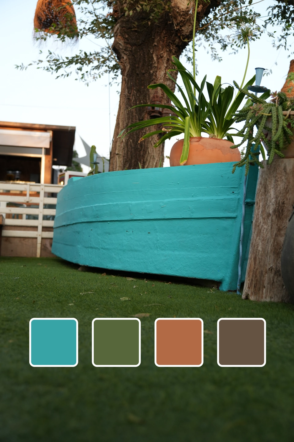 Carrusel de colores de Zaraho: Barca de madera turquesa usada como jardinera bajo un árbol, con muestras de color.